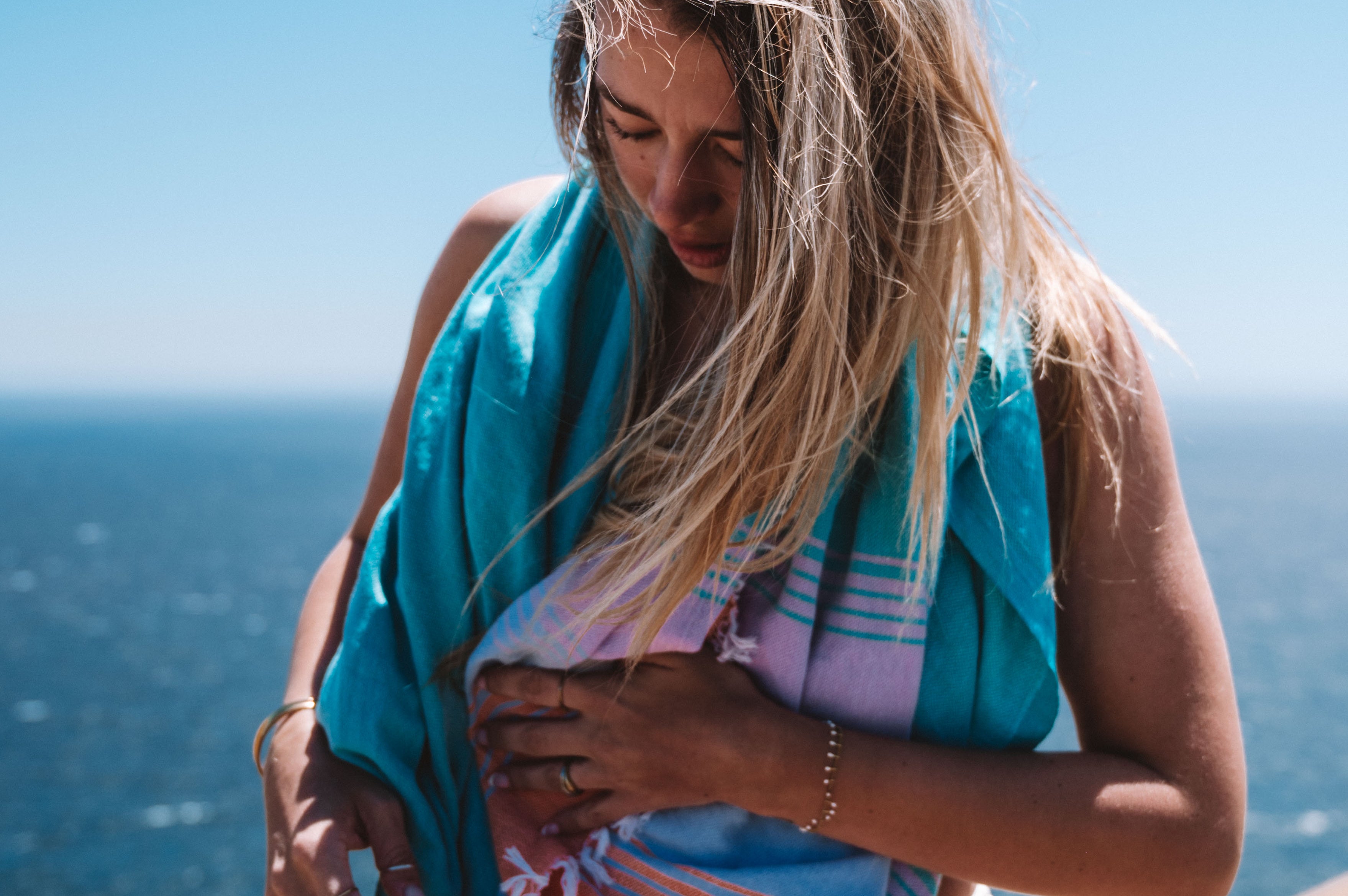Woman wrapped in the vibrant Fiesta towel by the sea – colorful and carefree summer vibe