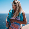Woman wrapped in the vibrant Fiesta towel by the sea – colorful and carefree summer vibe