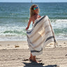 Woman happy at the beach with her Balmy Sienna towel