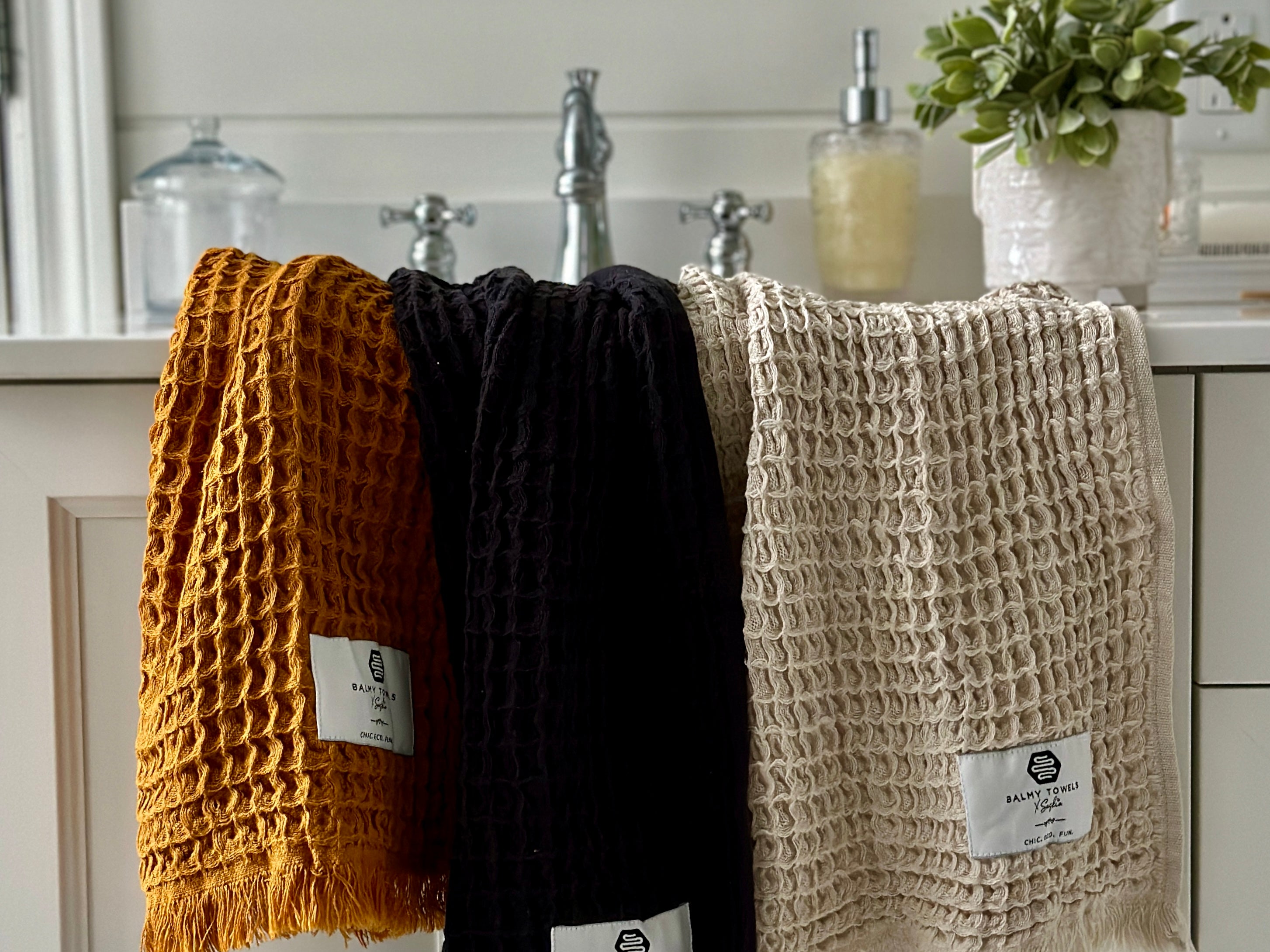 Waffle Mini hand towels in mustard, black, and beige, eco-friendly Turkish cotton, displayed in a modern bathroom
