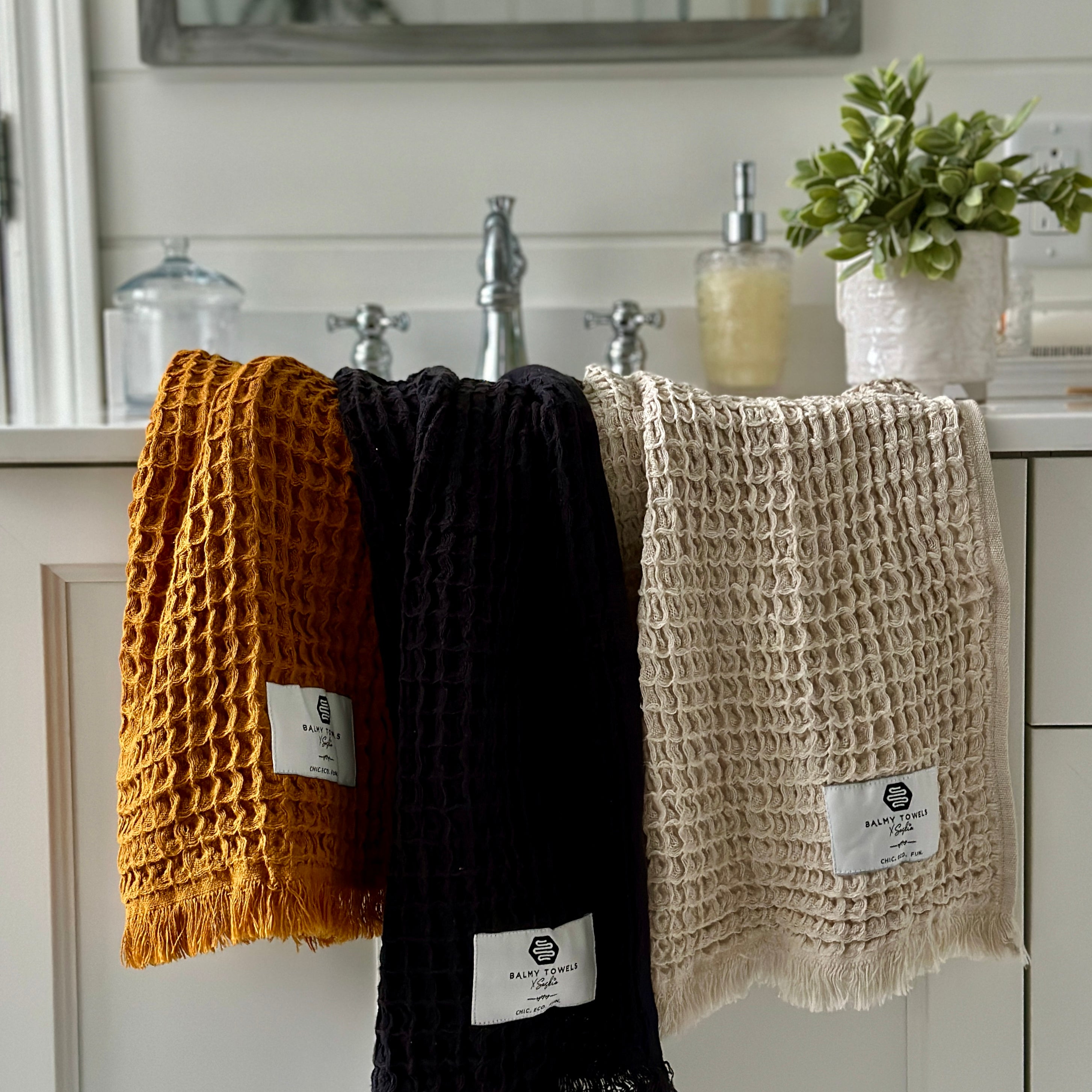 Waffle Mini hand towels in mustard, black, and beige, eco-friendly Turkish cotton, displayed in a modern bathroom