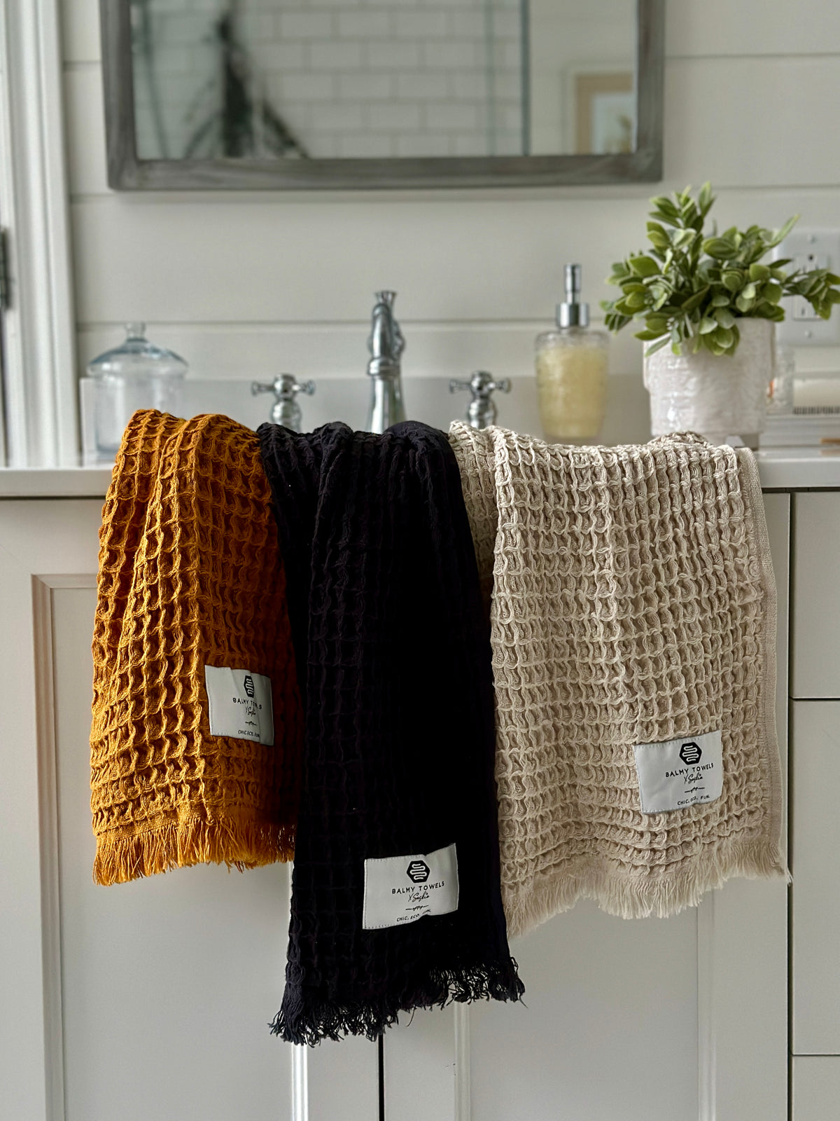 Waffle Mini hand towels in mustard, black, and beige, eco-friendly Turkish cotton, displayed in a modern bathroom