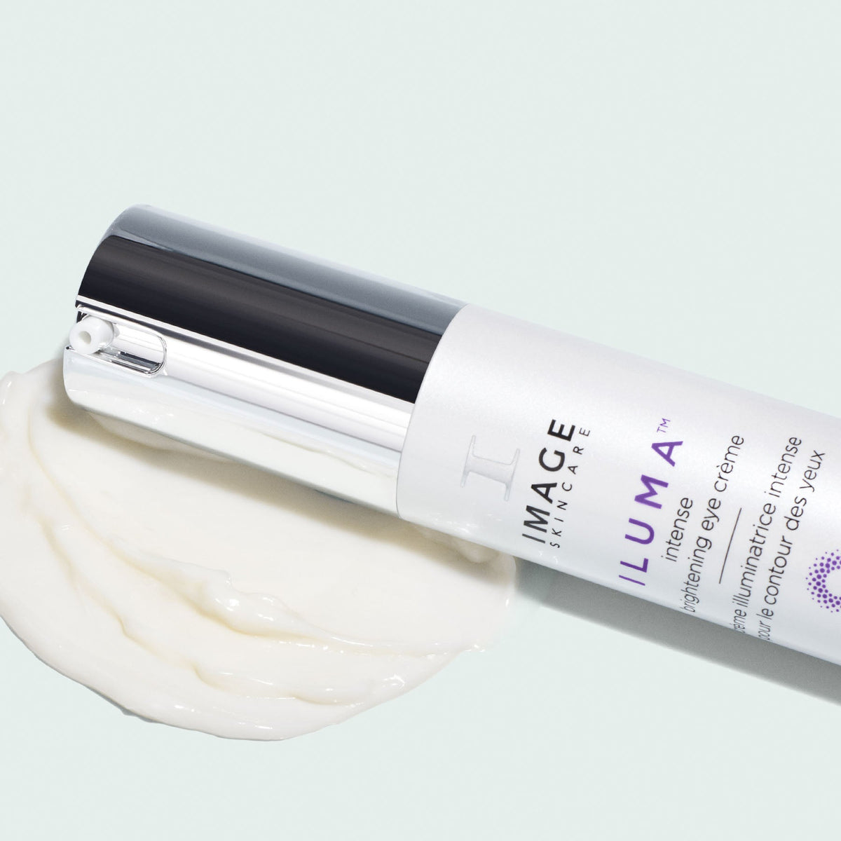 Image Skincare ILUMA intense brightening eye crème bottle lying on a swatch of white cream