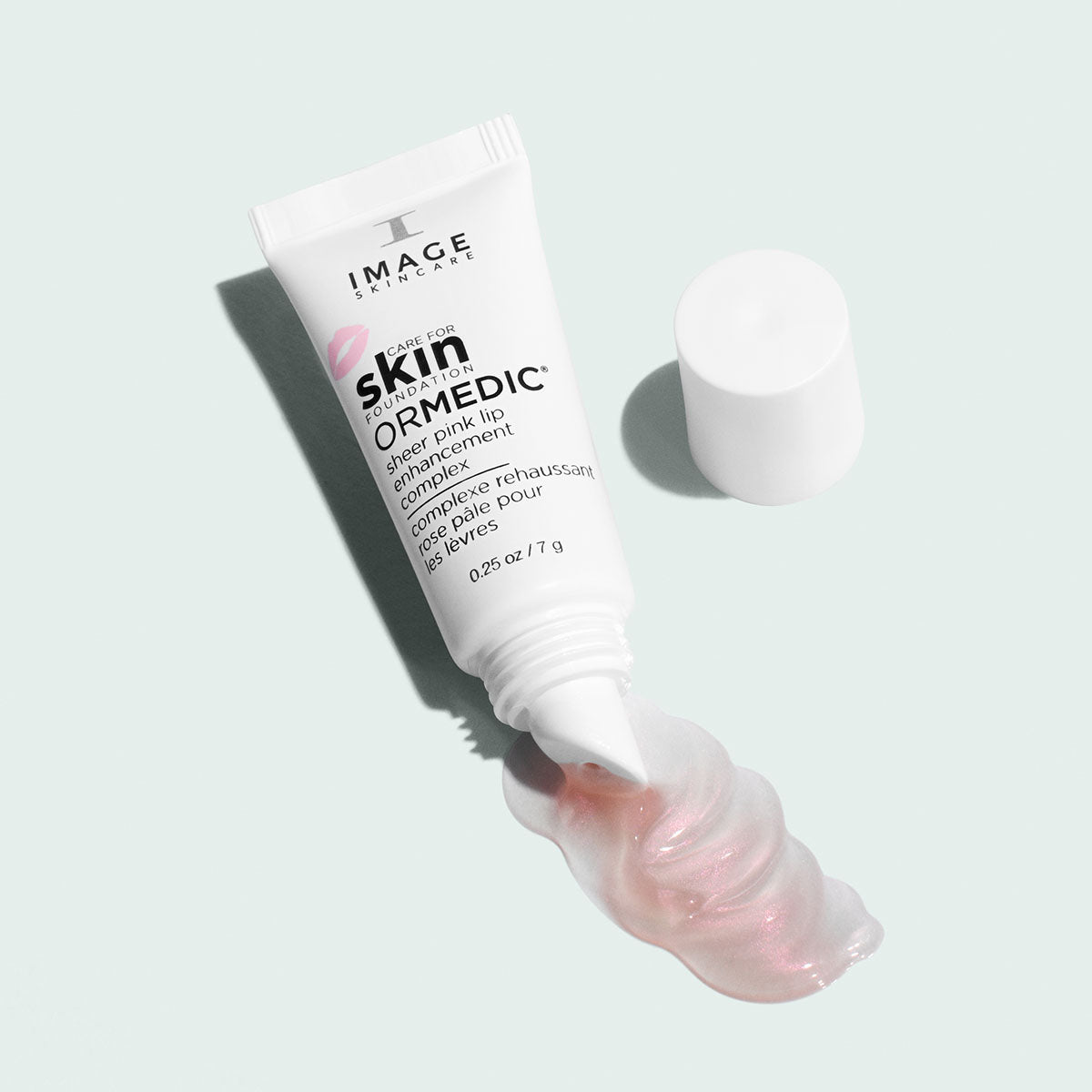 Tube ORMEDIC rose pâle pour les lèvres d’Image Skincare ouvert, bouchon à côté, filet de gloss rose nacré