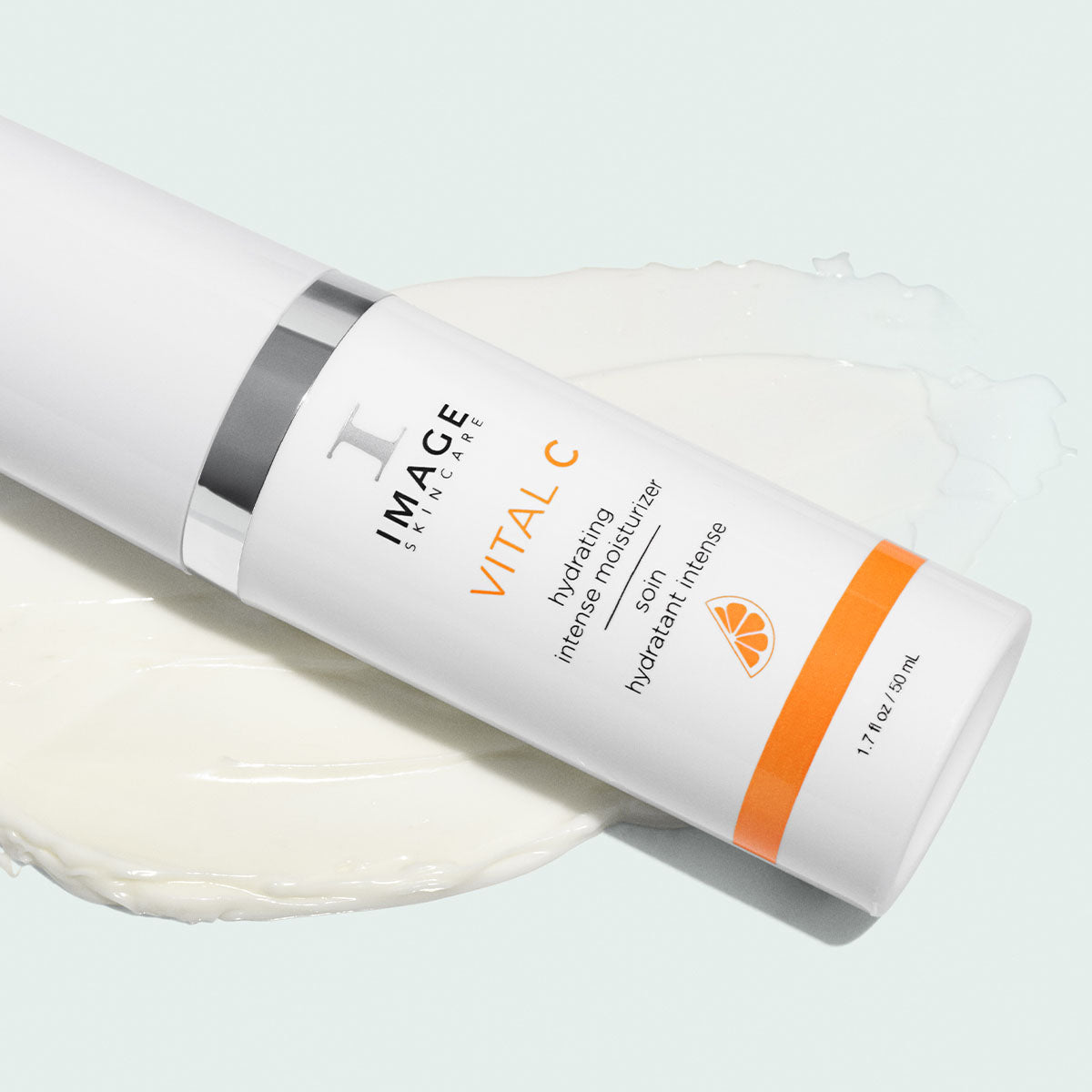 White Image Skincare VITAL C hydrating intense moisturizer bottle lying on a swatch of white cream, pale green background