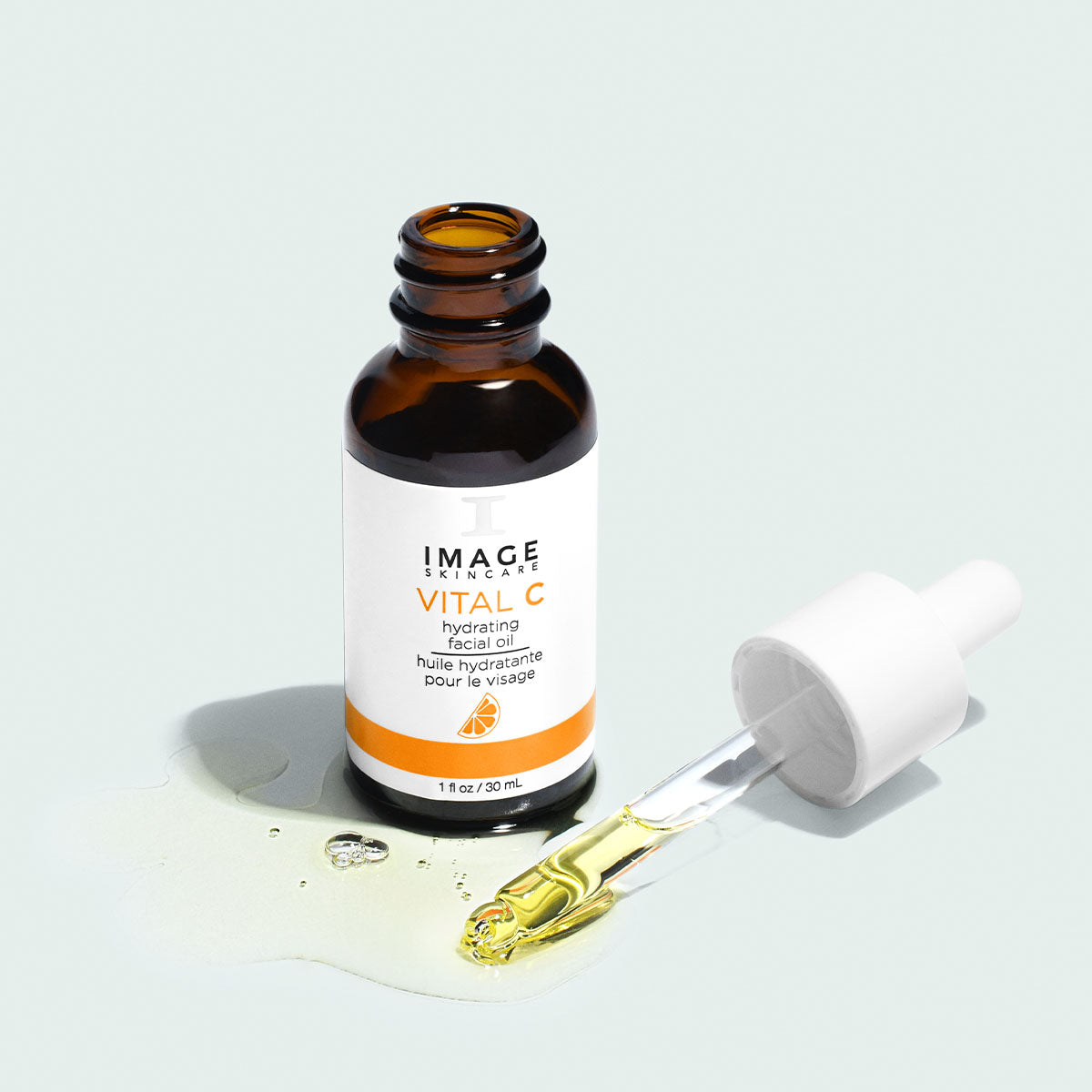 Open amber bottle of Image Skincare VITAL C hydrating facial oil, dropper resting in a small pool of oil