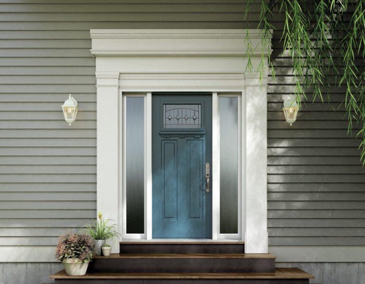 Porte d'entrée bleue entre deux panneaux latéraux en verre dépoli, sur une maison au revêtement gris, avec des plantes sur le perron